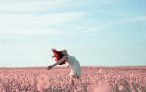 花畑で女性が空を仰ぎ見ている画像